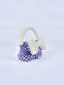 Dettaglio mini borsa in perle lilla intrecciate a mano con fiocchi di perle bianche