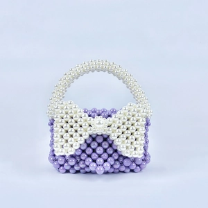 Dettaglio macro della borsa viola in perline fatta a mano con fiocco di perle bianche