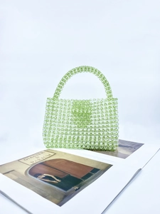 Detailed view of light green acrylic beaded handbag with clear beads on a magazine