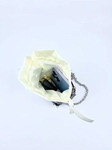 Top view of mini sequin bag interior with smartphone and makeup on a bright background