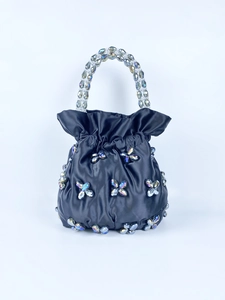 Close-up of black satin pouch bag with crystal butterfly and clear beaded handle