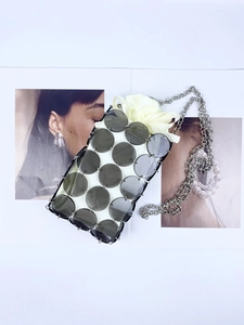 Detailed macro shot of grey acrylic disc mini bag with metal rings and white satin pouch
