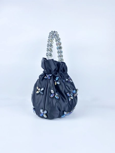 Detail of black satin drawstring bag with butterfly charms and beaded handle