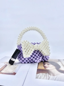 Dettaglio della borsa fatta a mano con perle viola e un grande fiocco di perle bianche