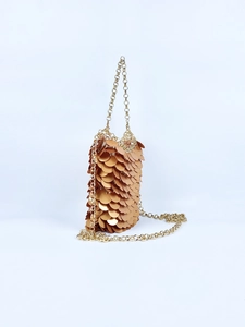 Macro detail of overlapping gold metallic sequins and chain strap of this sequin bucket bag