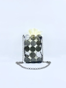 Detail view of sparkly dark grey sequins and silver metal rings on a woven mini bag