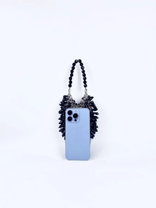 Detail view of black beaded handbag with silver chain next to a smartphone for scale