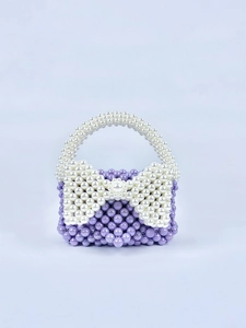 Dettaglio di mini borsa fatta a mano in perle lavanda con fiocco di perle bianche
