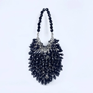 Macro detail of geometric black acrylic beads on a luxury evening handbag with silver hardware
