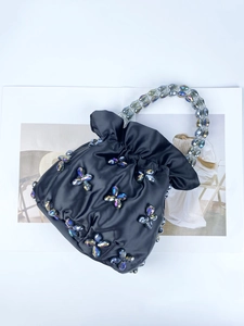 Detail view of black satin handbag with handcrafted crystal butterfly beads and top handle