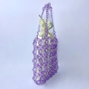 Detailed shot of purple beaded handbag featuring a white satin drawstring inner bag