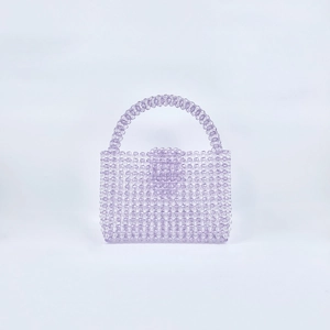 Macro detail of handmade lavender acrylic beads on a mini woven top handle square bag