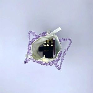 Detail view of purple handmade beaded bag with white satin drawstring pouch and daily items