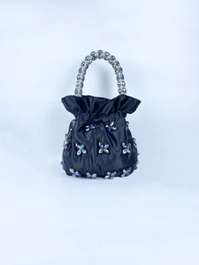 Detail of black satin handbag featuring crystal butterfly accents and beaded handle