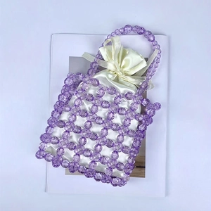 Close-up of purple beaded handmade handbag with white satin drawstring pouch detail