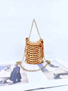 Detail of a gold sequin bucket bag with interlocking metallic disks and chain strap