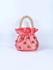 Detail of pink satin bucket bag featuring green bead accents and beaded handle