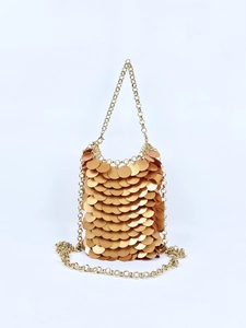 Macro detail of golden fish scale sequins and metallic chain on high-fashion evening bag