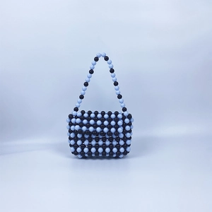 Détail d'un sac à main artisanal avec des perles noires et bleues au design tissé