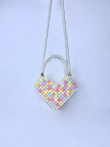 Macro detail of a colorful beaded heart-shaped mini bag with pearly strap and accents