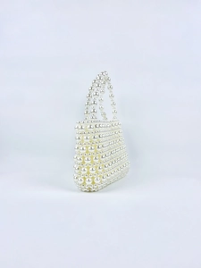 Detailed view of the woven pearl handbag with glossy cream beads and a top handle