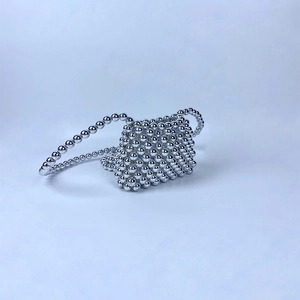 Detailed view of silver beaded mini crossbody bag with glossy metallic finish and woven strap