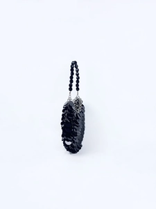 Détail de sac à paillettes noires avec anse en perles et anneaux métalliques argentés