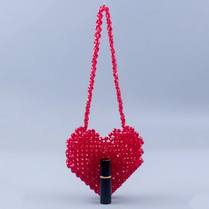 Detailed view of red heart beaded mini bag with pearls and lipstick for size scale