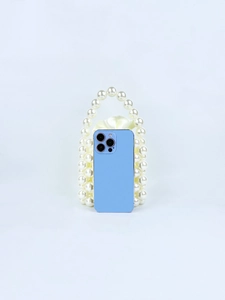 Vista dettagliata di una mini borsa di perle bianche accanto a uno smartphone blu