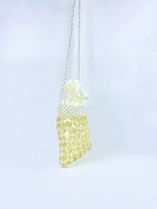 Detail view of handmade beaded bag showing yellow crystals and white pearls texture