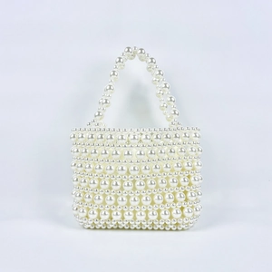 Macro detail of hand-woven pearl beaded handbag with elegant textured pattern