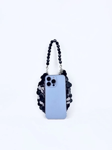 Détail des paillettes noires en écailles et poignée en perles sur petit sac mobile