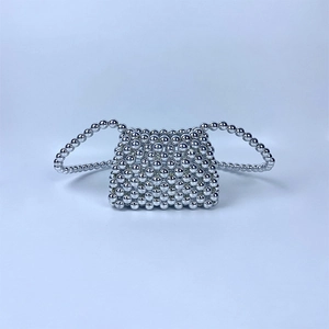 Close-up of silver beaded woven mini bag with metallic finish and trapezoid silhouette