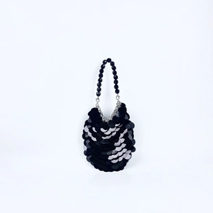 Détail de paillettes noires en écailles et poignée perlée sur un mini sac de fête