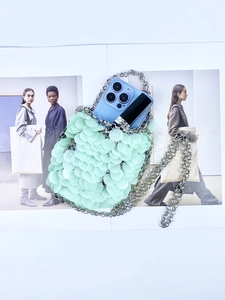 Detail view of mint green sequin shoulder bag showing interior space for phone and lipstick