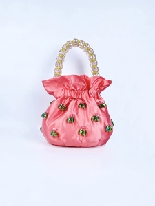 Close-up of pink satin handbag with green crystal beads and a beaded handle detail