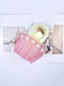 Pink beaded handmade basket bag with white pearl flowers and satin lining on a magazine