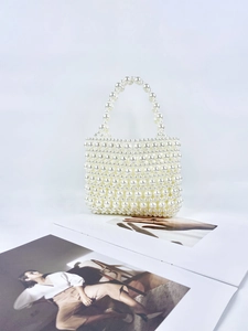 Detail of handcrafted cream pearl woven handbag featuring elegant large and small beads