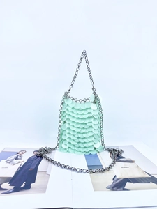 Detailed macro view of mint green sequins and silver chain on a trendy bucket bag