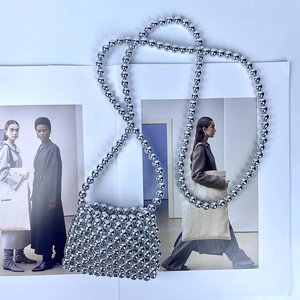 Detailed view of handmade silver beaded mini crossbody bag on a fashion magazine