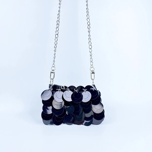 Détail du sac bandoulière à paillettes noires avec chaîne argentée et texture écailles