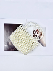 Detailed view of cream pearl woven handbag showing intricate beaded texture and flap design