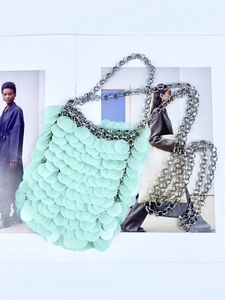 Close-up of mint green sequin chain bag with acrylic discs on a fashion magazine
