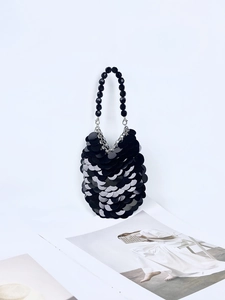 Détail des paillettes noires en écailles et de l'anse perlée sur un mini sac à main