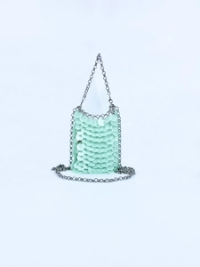 Macro detail of mint green sequin disc handbag with silver chain strap and layered texture