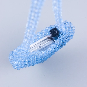 Detailed top view of light blue beaded crossbody bag holding a lipstick and earbud case