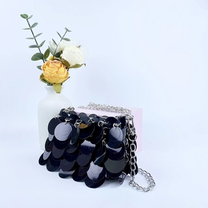 Détail d'un sac bandoulière à paillettes noires avec chaîne argentée et décor floral