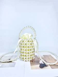 Detail of handmade pearl bucket bag with gold accents and drawstring satin pouch liner