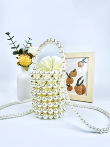 Detail of handmade pearl bucket bag with gold accents and yellow satin drawstring