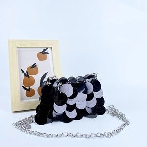 Détail d'un sac bandoulière à paillettes noires avec une fine chaîne argentée chic